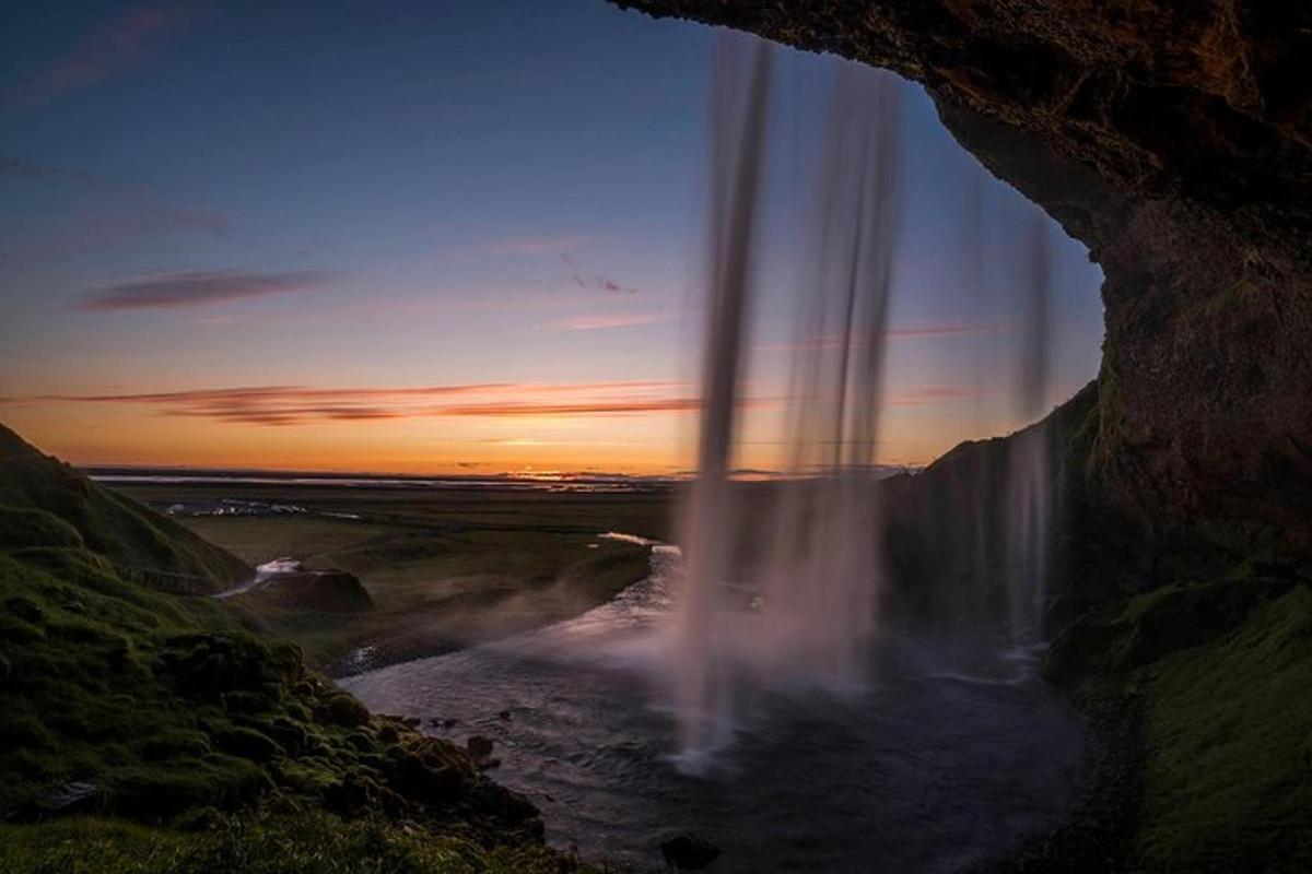 una vista di una cascata da una grotta al tramonto