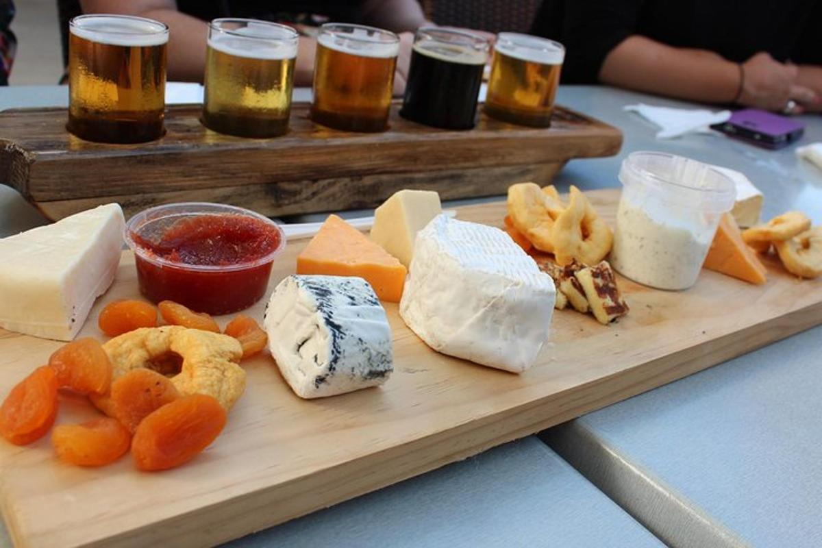 a wooden tray with cheese and other appetizers and beers