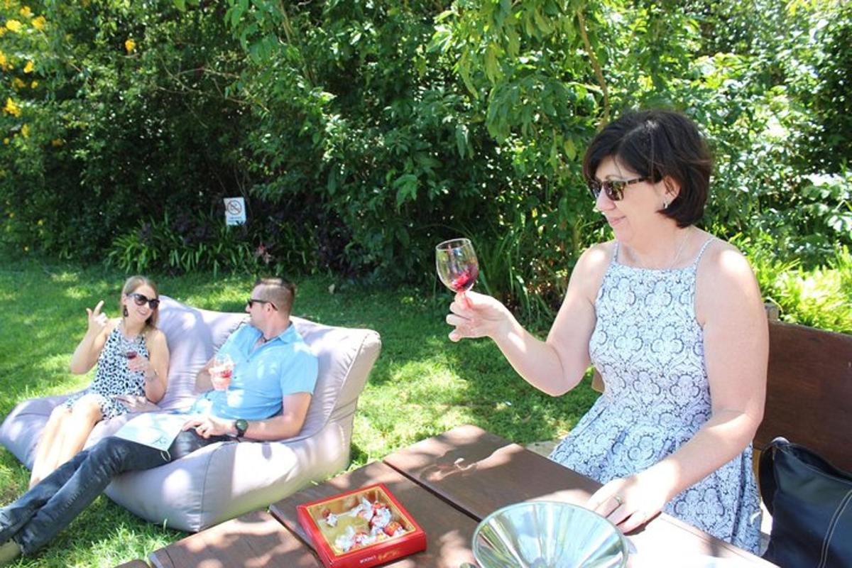 a woman holding a glass of wine with two people sitting on a couch