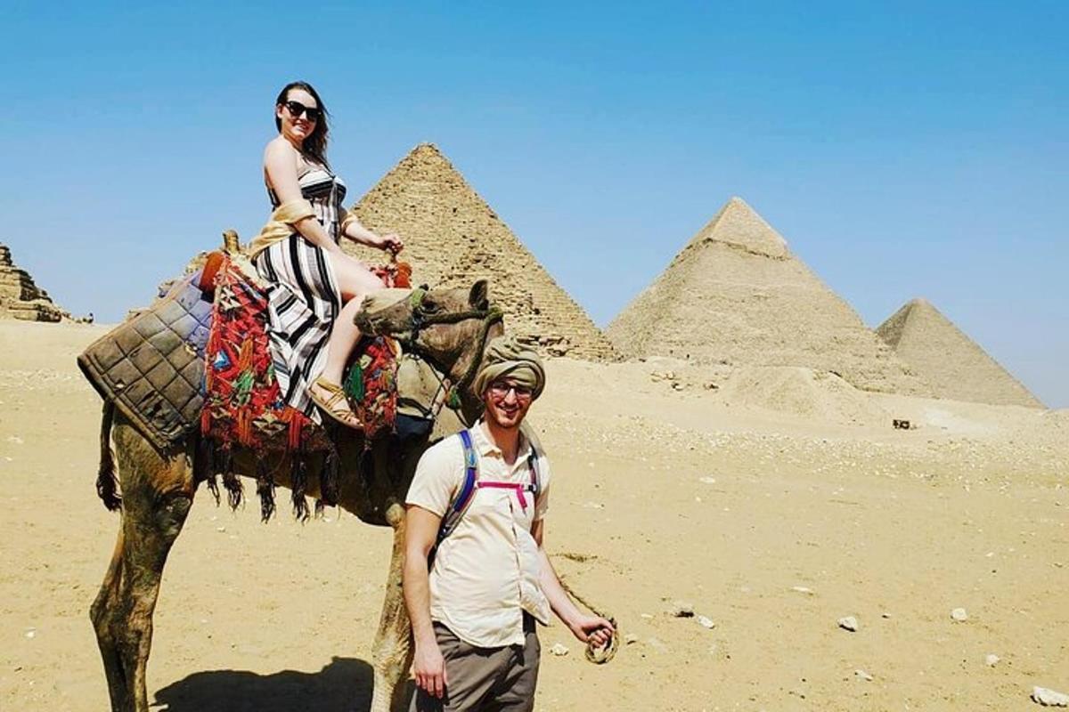 Un hombre de pie junto a una mujer montando un elefante en las pirámides.