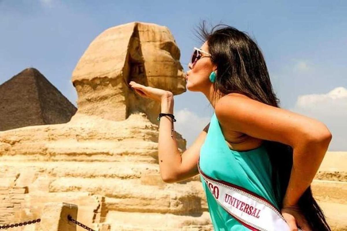 a woman in a dress standing next to a pyramid