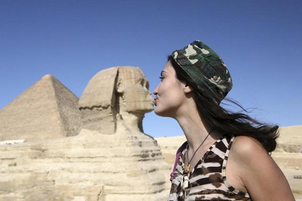 a woman standing in front of the sphinx and the pyramid