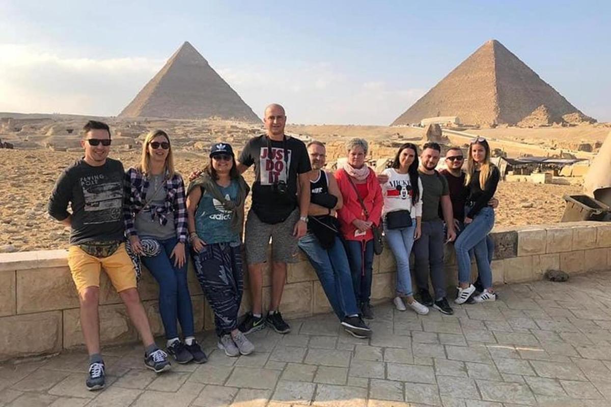 a group of people standing on a wall in front of pyramids