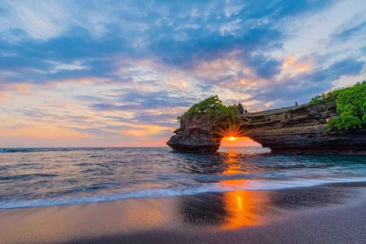 Západ slunce nad oceánem poblíž velkého skalního útvaru