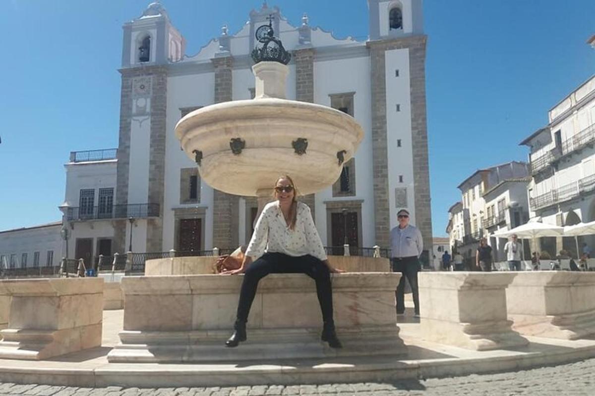 Una mujer sentada en una fuente frente a un edificio.
