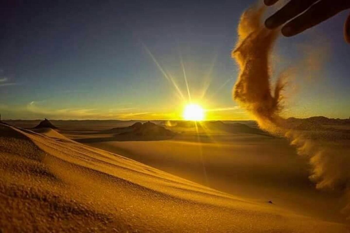 a sunset in the desert with the sun in the sky