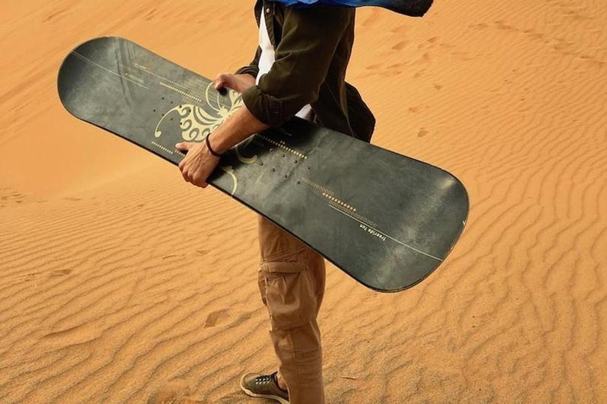 a man holding a skateboard in the desert