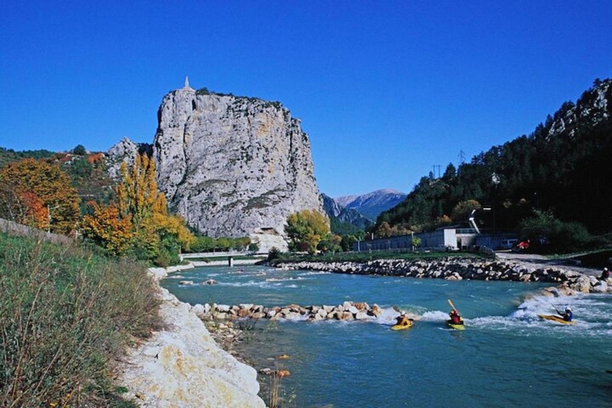 a group of people kayaking down a river with a mountain