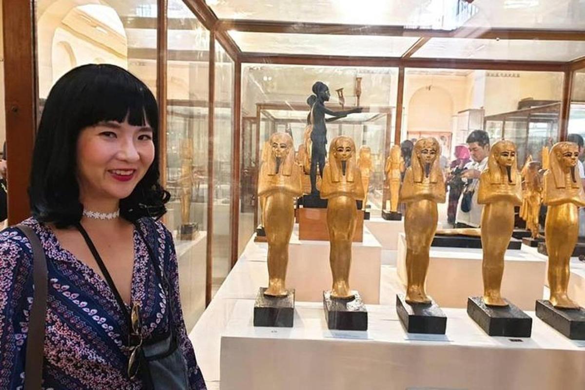 Una mujer parada frente a una exhibición de estatuas doradas