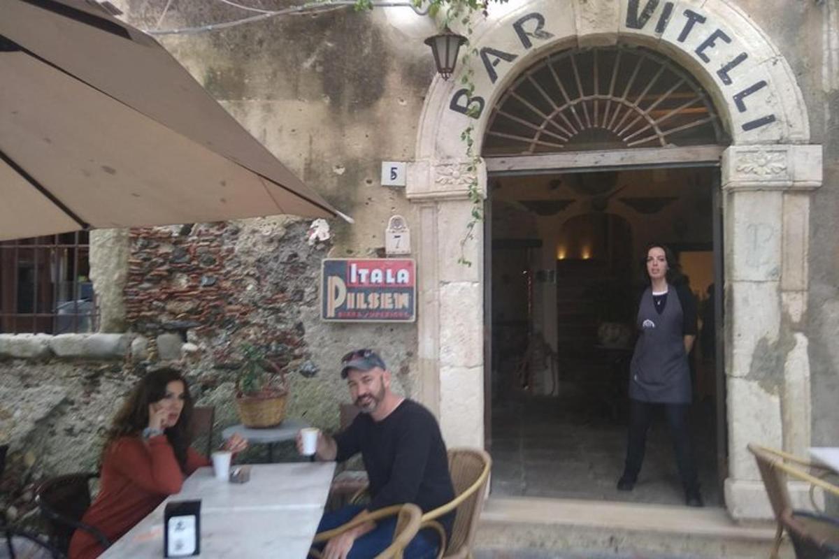skupina lidí sedících u stolu před restaurací