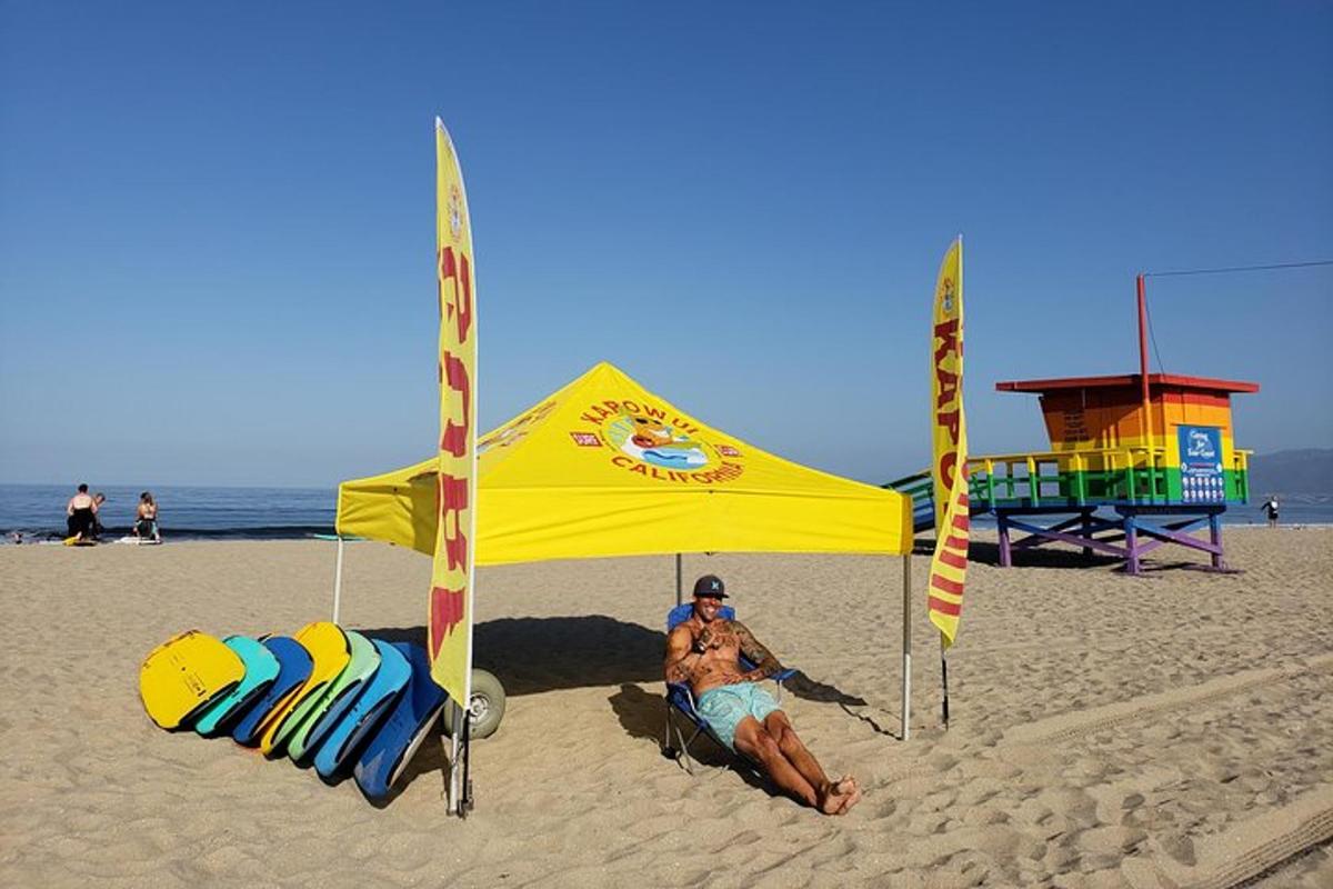un home assegut sota una tenda a la platja