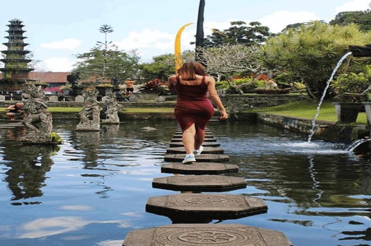 ผู้หญิงกำลังข้ามสะพานเหนือสระน้ำในสวนสาธารณะ
