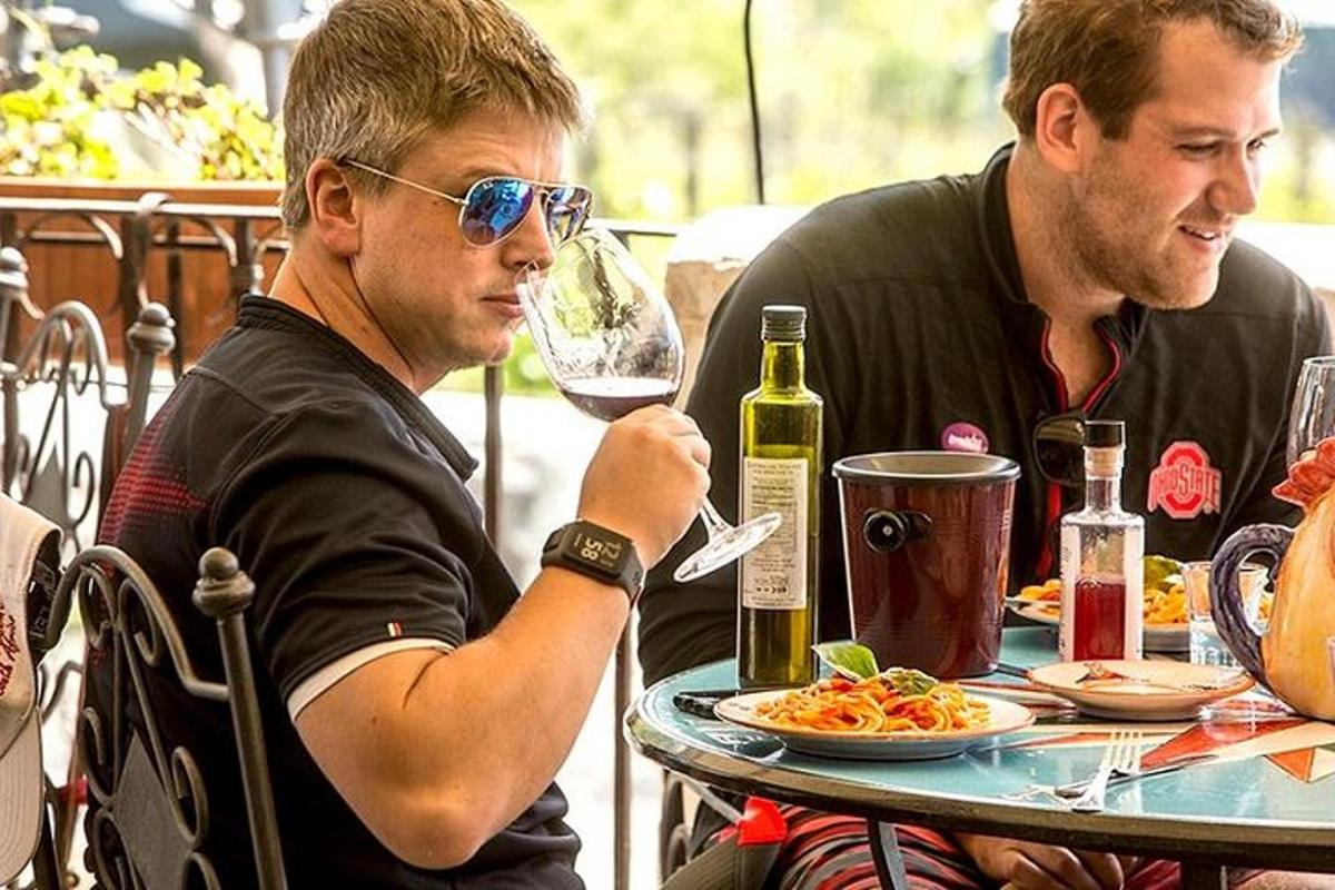 dva muži sedící u stolu se sklenkou vína