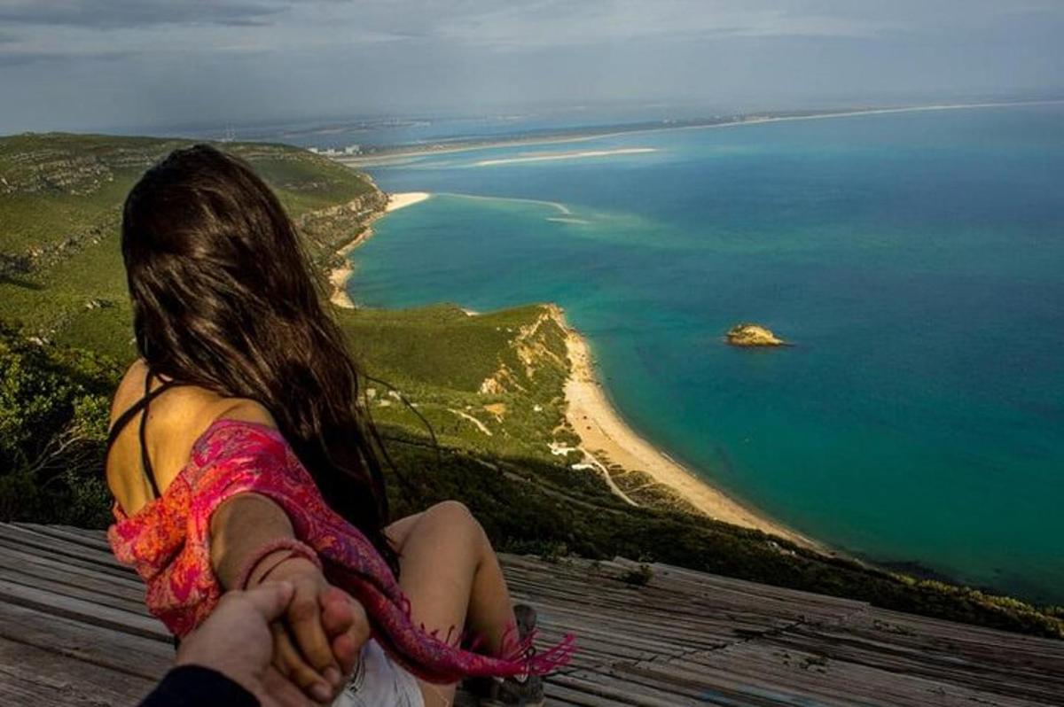 žena sedící na vrcholu kopce a dívající se na oceán
