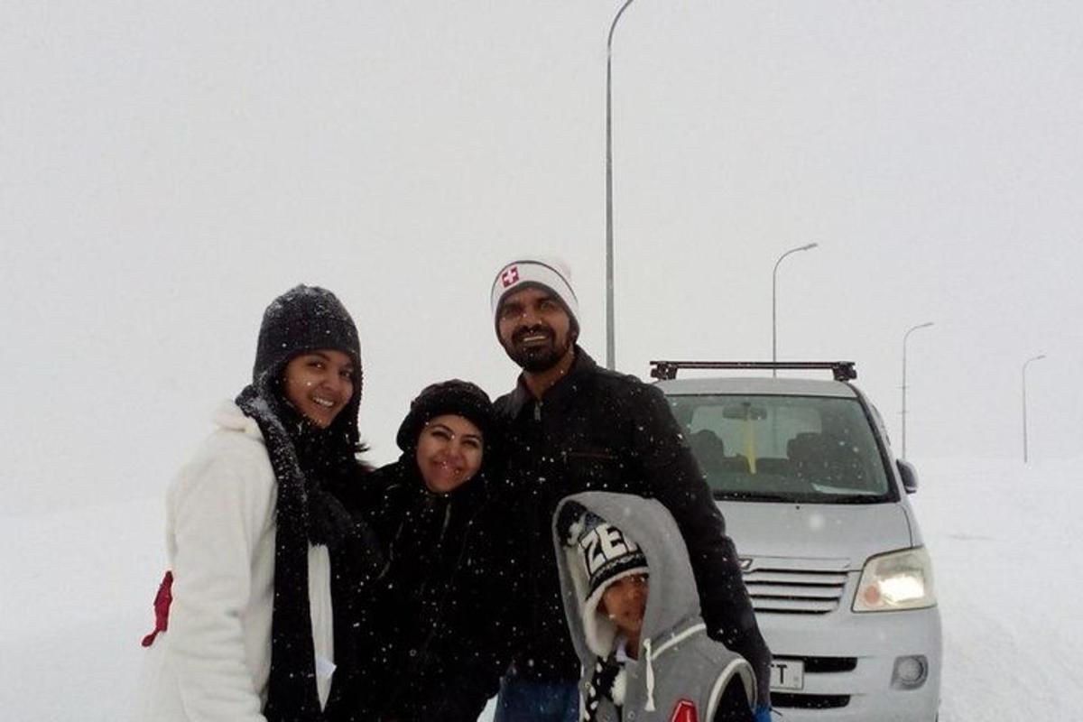 un grup de oameni care stă în zăpadă cu o placă de snowboard