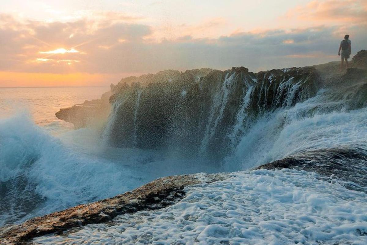 muž stojící na vrcholu vodopádu u oceánu