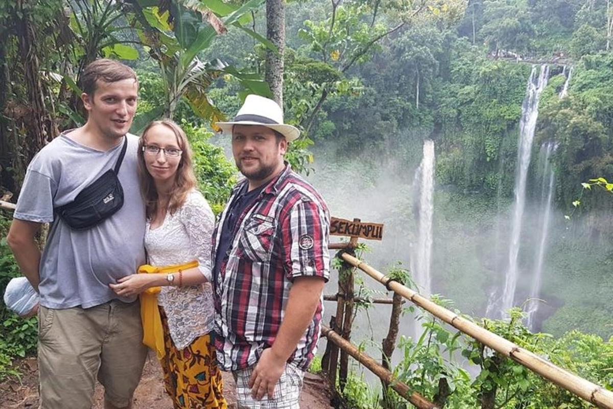 dois homens e uma mulher em pé em frente a uma cachoeira