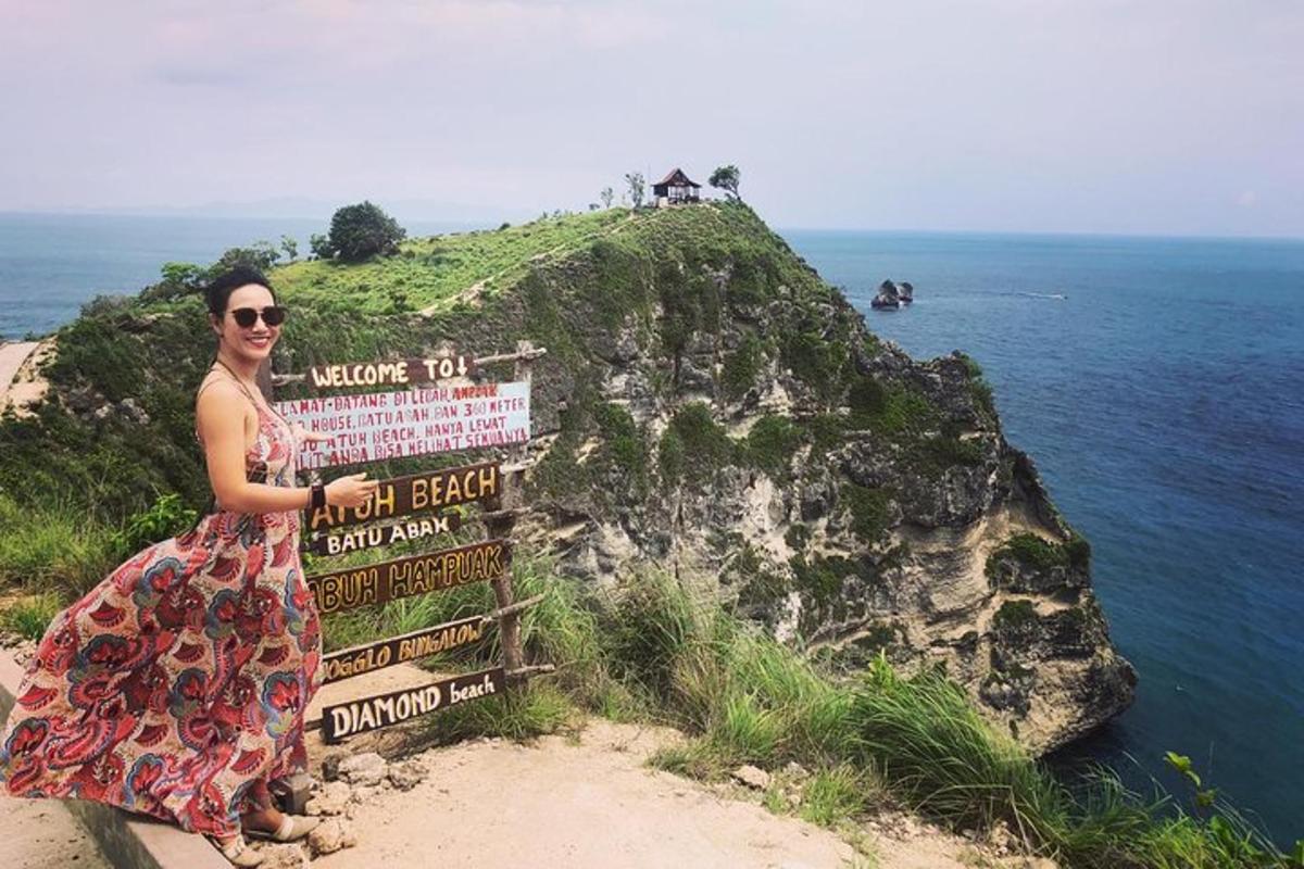 žena v šatech stojící vedle cedule na útesu