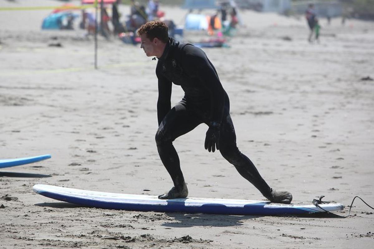 un uomo è in piedi su una tavola da surf sulla spiaggia