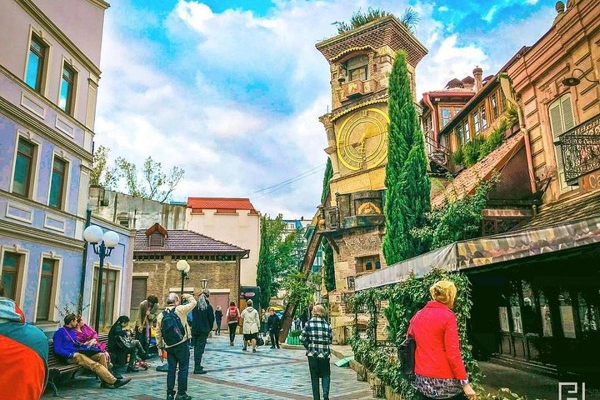 μια ομάδα ανθρώπων που περπατούν σε έναν δρόμο με έναν πύργο ρολογιού