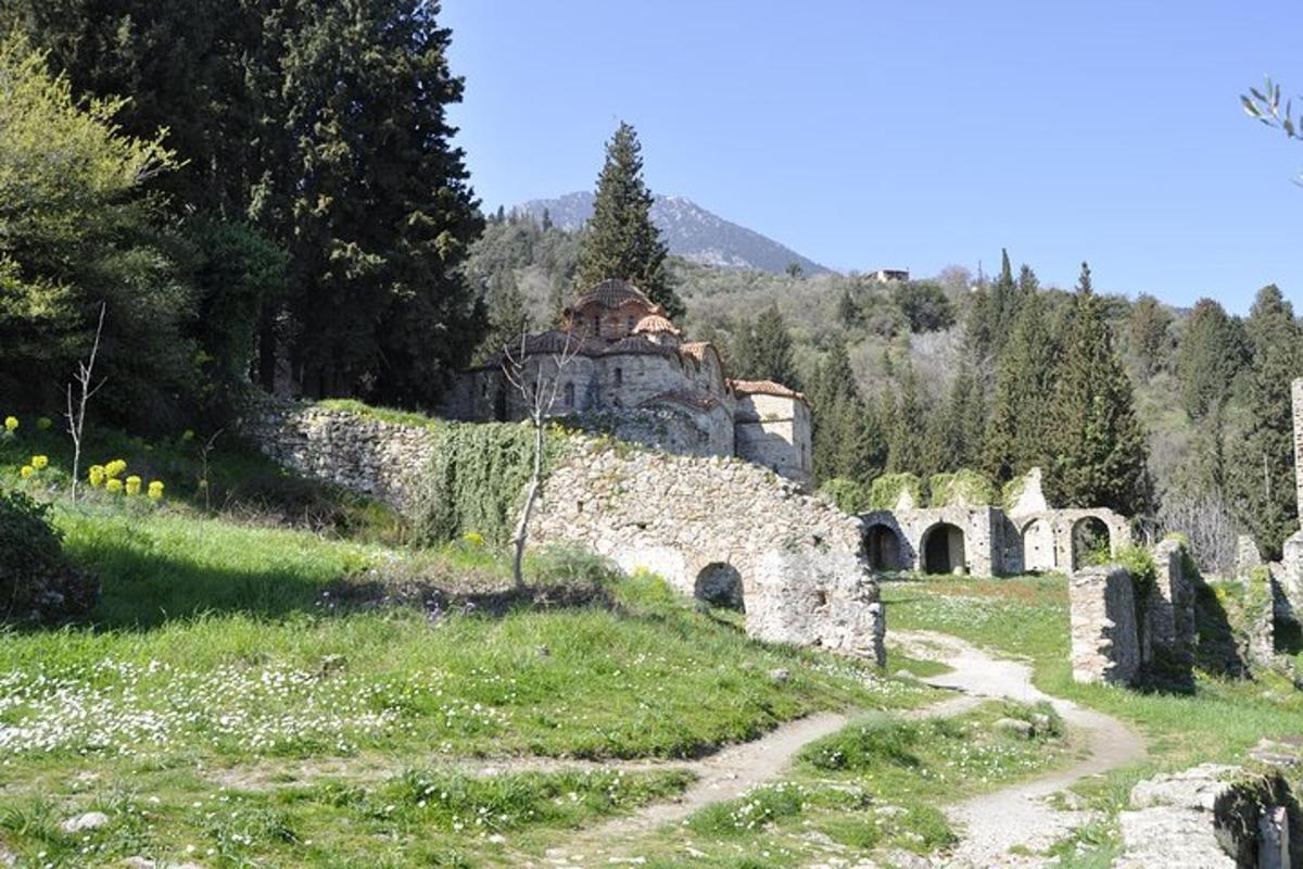 ένα παλιό πέτρινο κτίριο σε έναν λόφο με χωματόδρομο