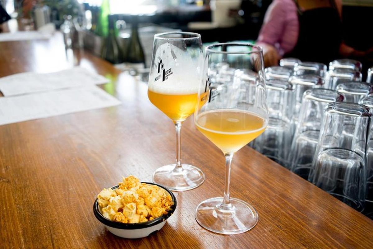 two glasses of beer and a bowl of popcorn on a table
