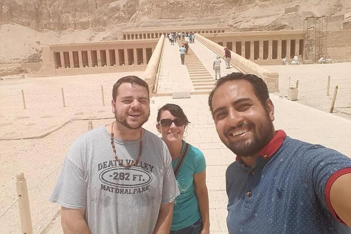 Δύο άνδρες και μια γυναίκα στέκονται μπροστά σε μια πυραμίδα