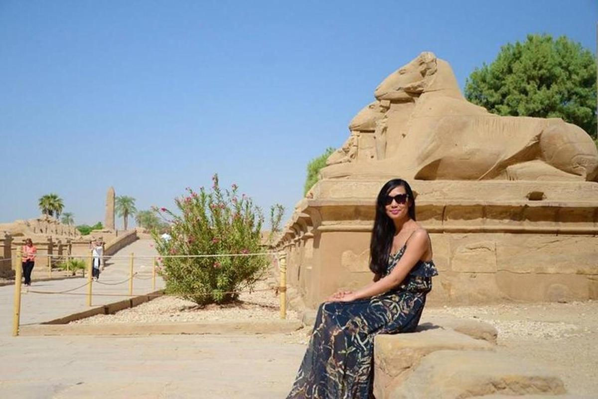 una donna in abito seduta accanto a una statua