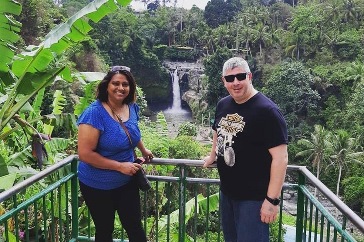 a man and a woman standing in front of a waterfall