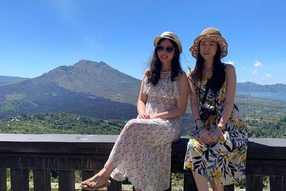two women sitting on a bench with a mountain in the background
