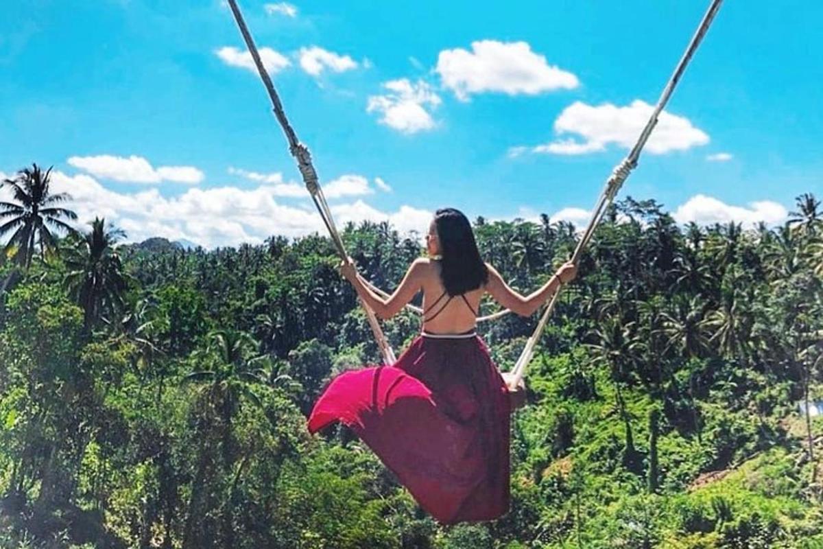 Una mujer en un columpio frente a un bosque.