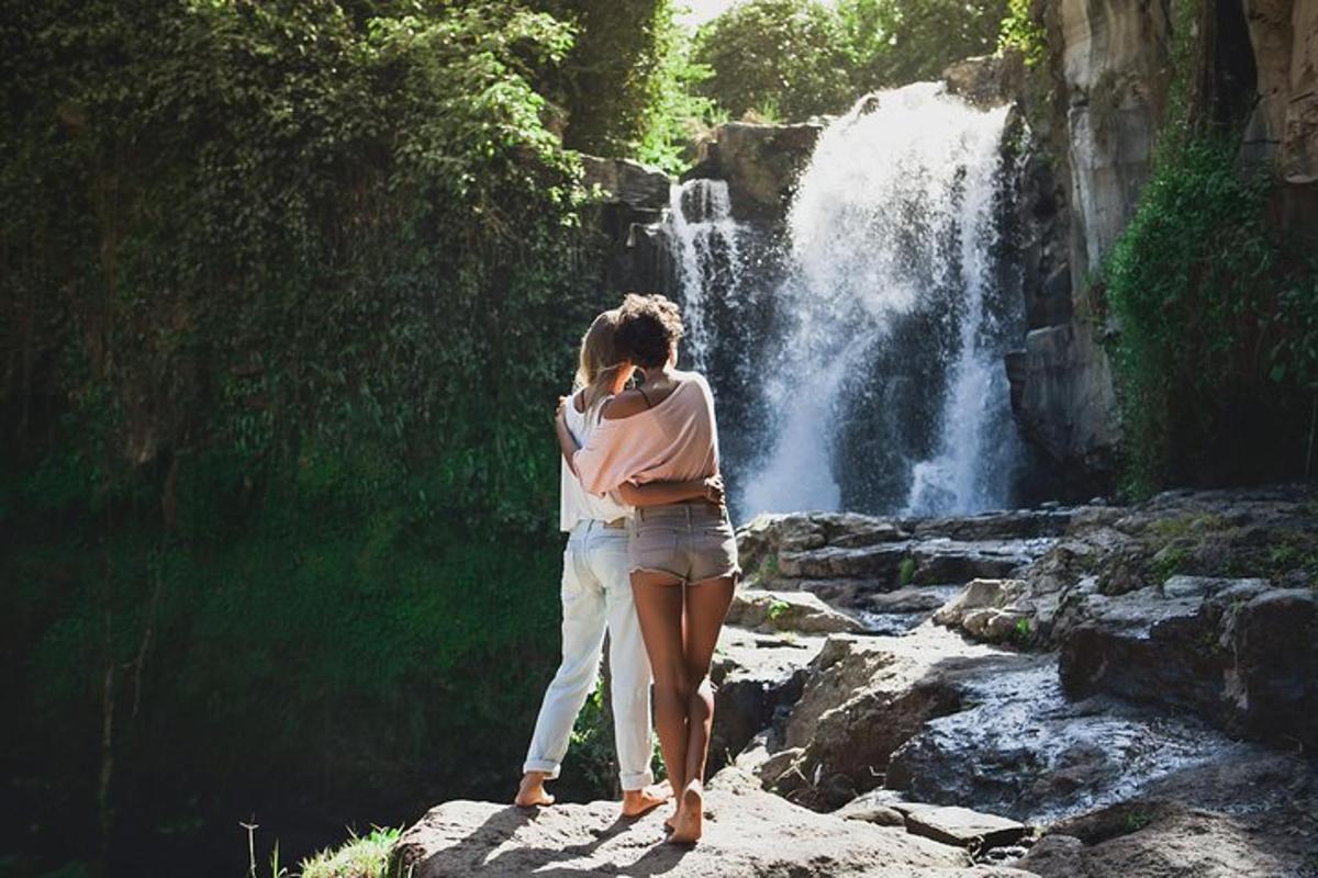una donna in piedi su una roccia di fronte a una cascata