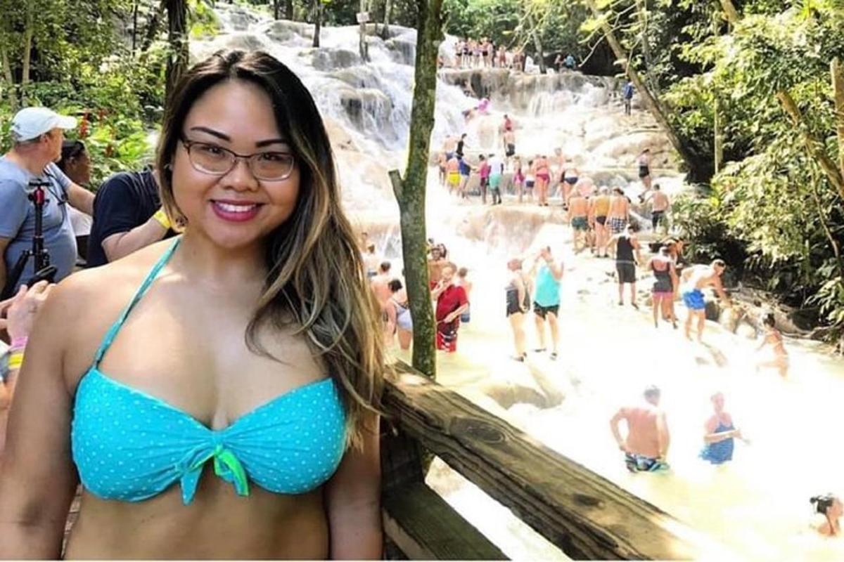 seorang wanita berbikini biru berdiri di depan air terjun