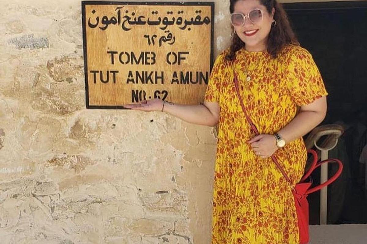 una dona amb un vestit groc dempeus al costat d'un rètol