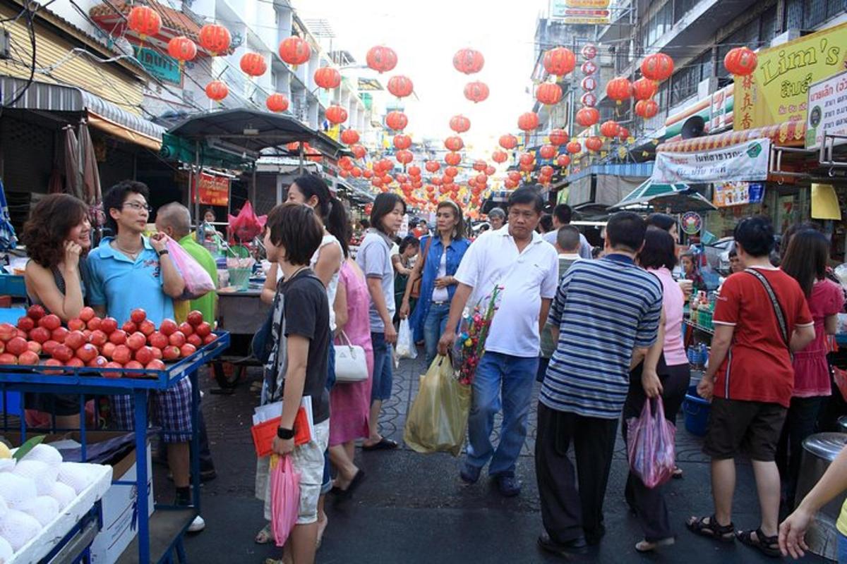 una folla di persone che camminano in un mercato con lanterne rosse