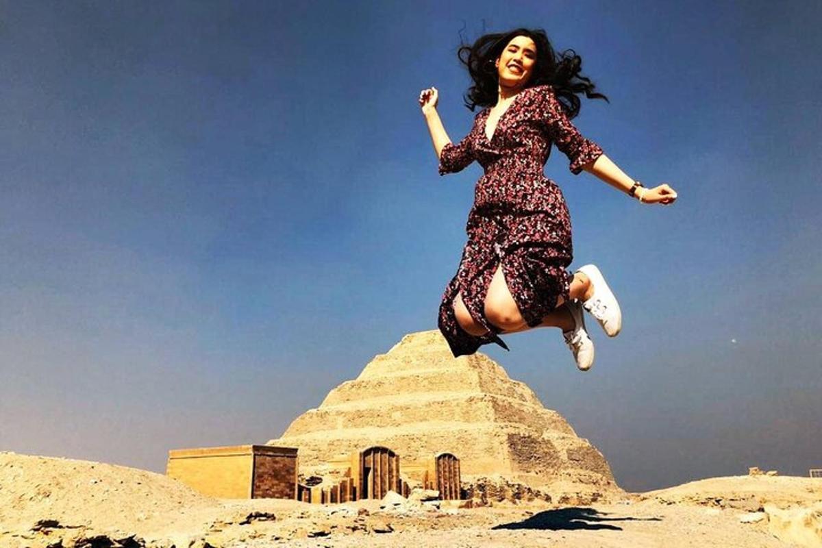 una donna che salta in aria davanti a una piramide