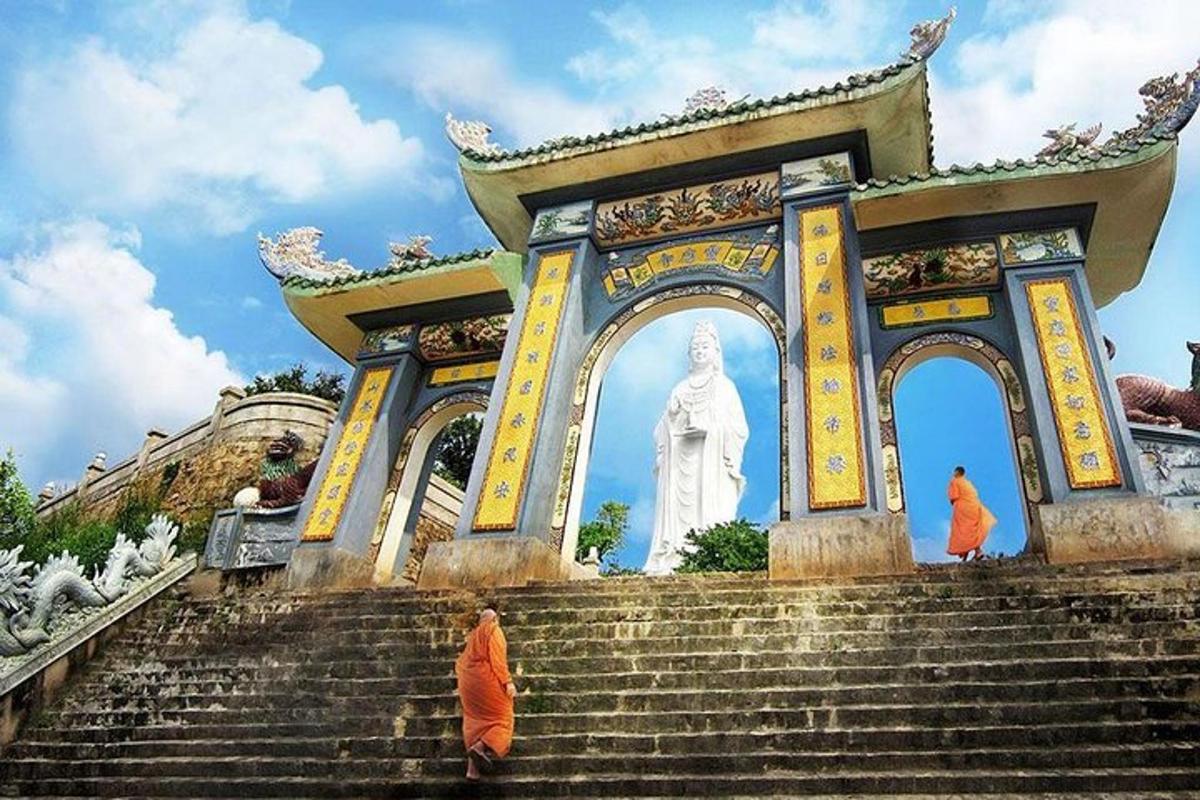 một người phụ nữ mặc đồ màu cam đang ngồi trên cầu thang trước một bức tượng