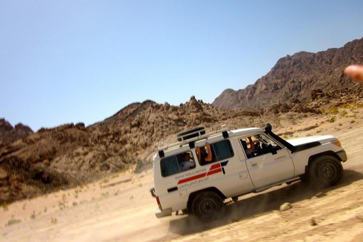 a white truck driving on a dirt road in the desert
