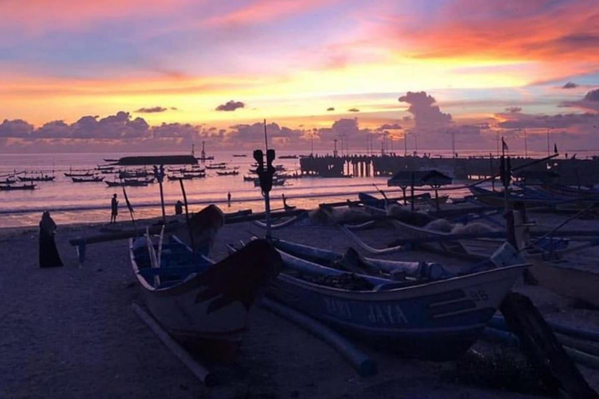 Un grupo de barcos sentados en la playa al atardecer