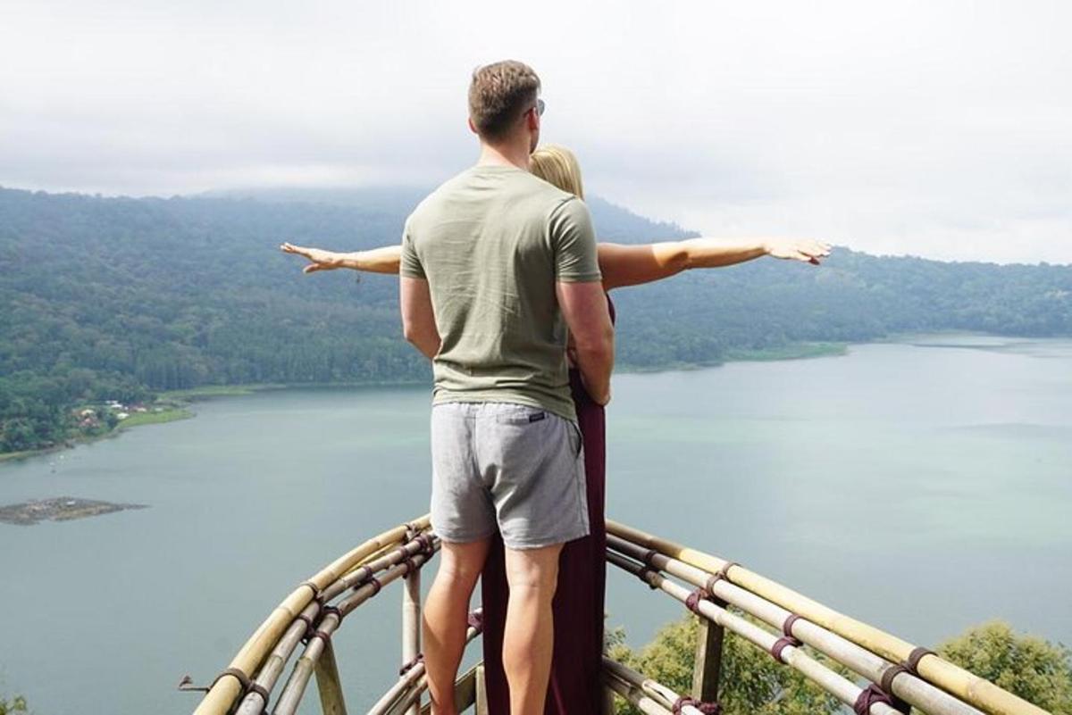 un uomo e una donna in piedi in cima a un ponte panoramico che domina un lago