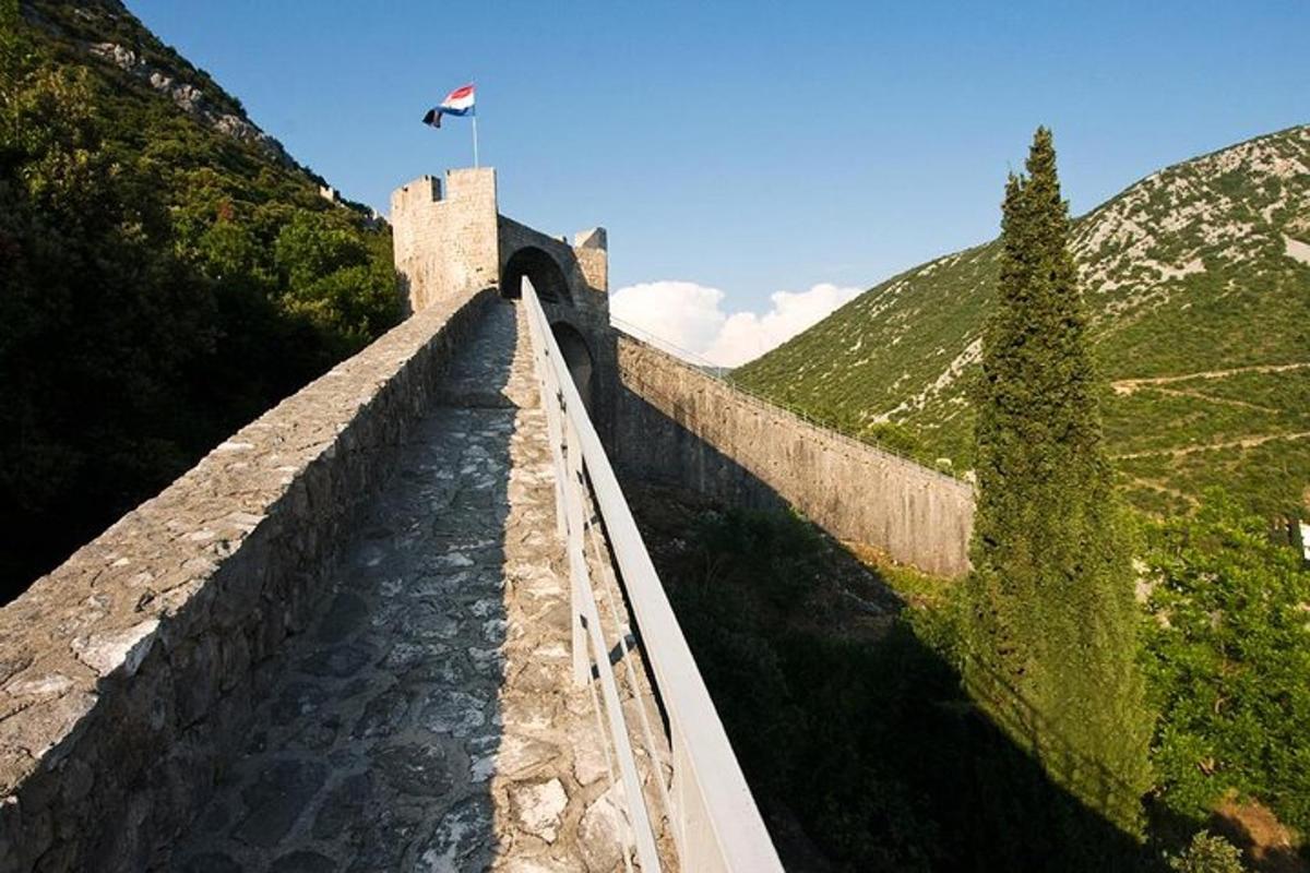um muro de pedra com uma ponte sobre um rio
