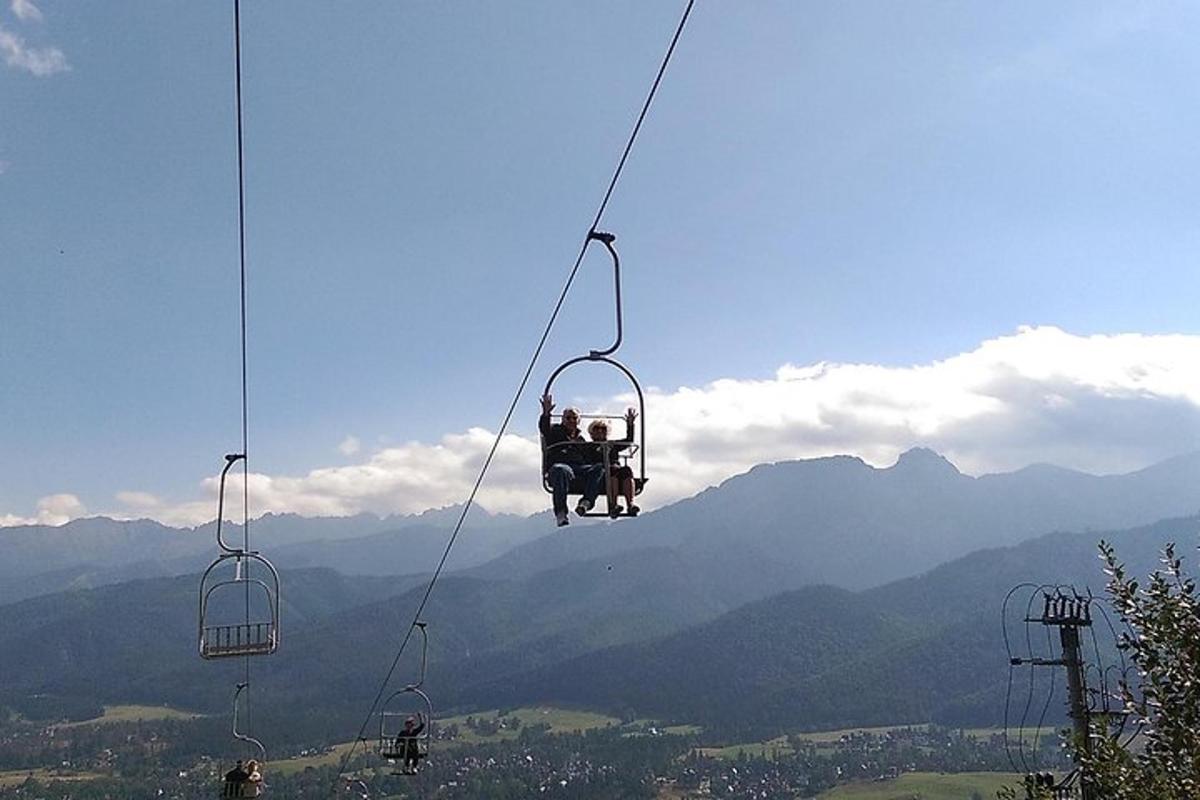 dva lidé jedoucí na lyžařském vleku v horách