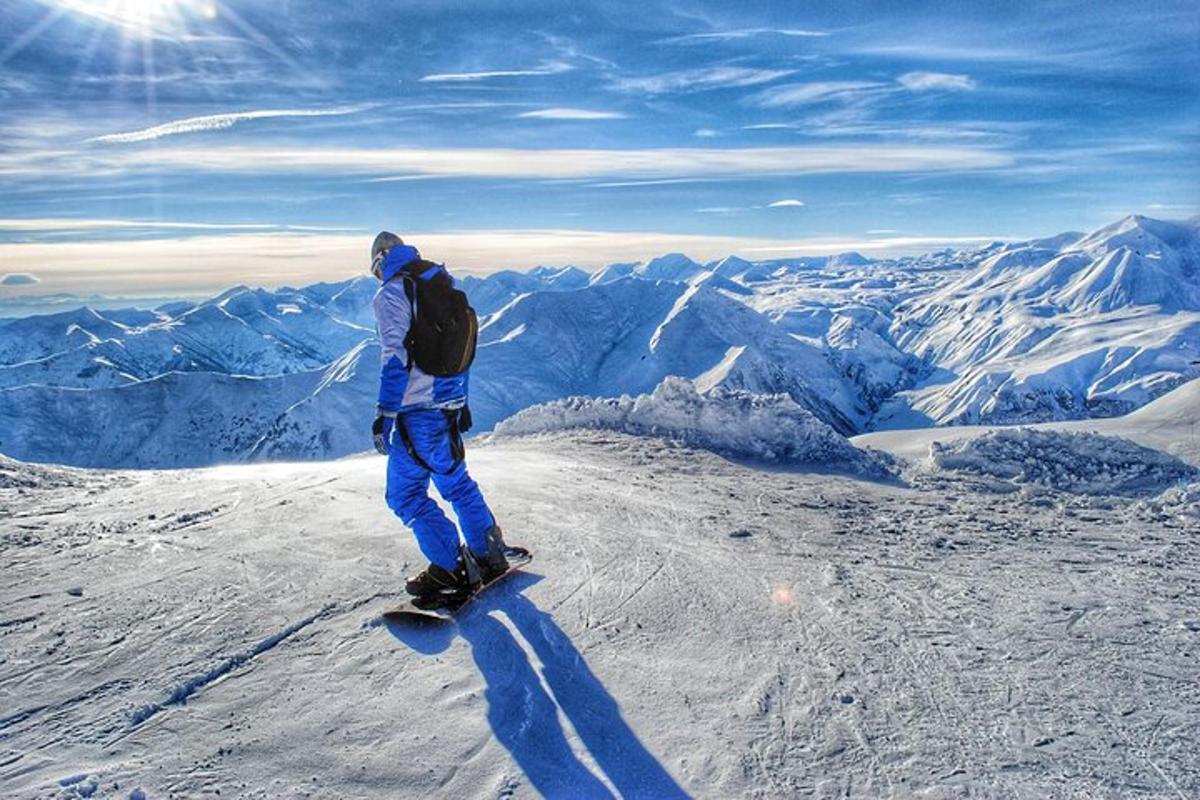 muž jedoucí na snowboardu na vrcholu hory