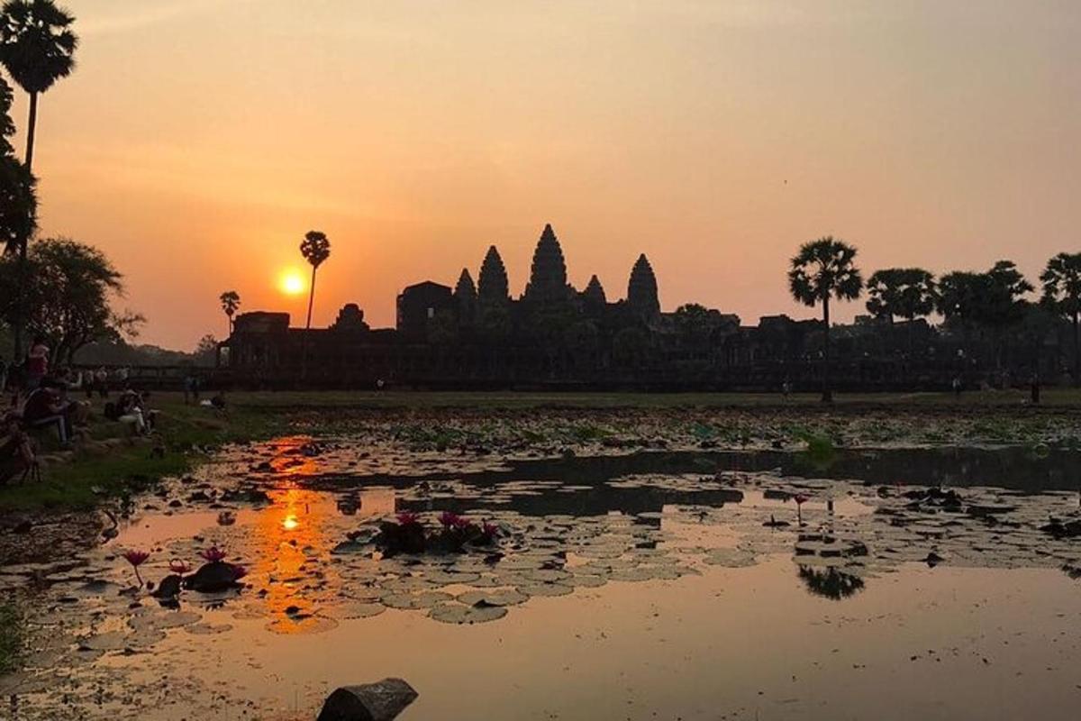 a sunset over a pond in front of a temple