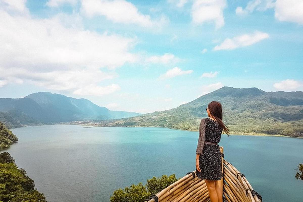 a woman standing on a ledge overlooking a lake