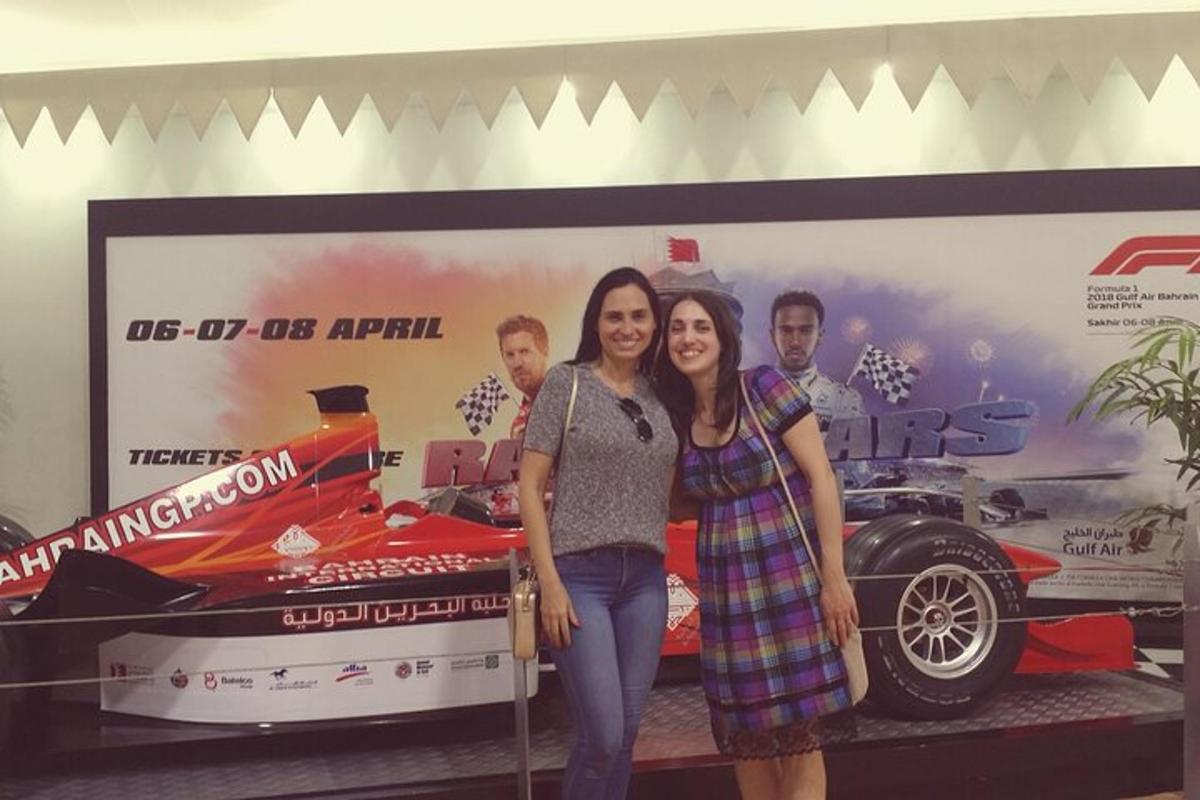 two women standing next to each other in front of a car
