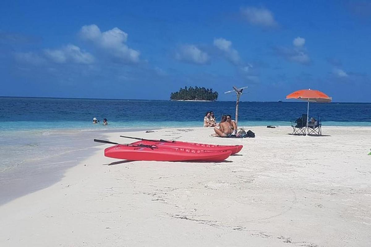 rdeč čoln na plaži z ljudmi na vodi