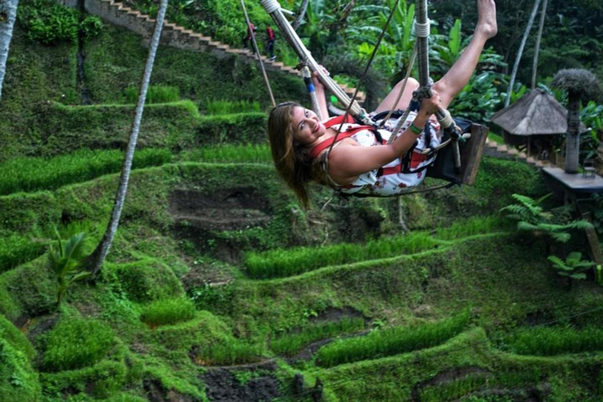 žena houpající se na zip line nad mechem pokrytým polem