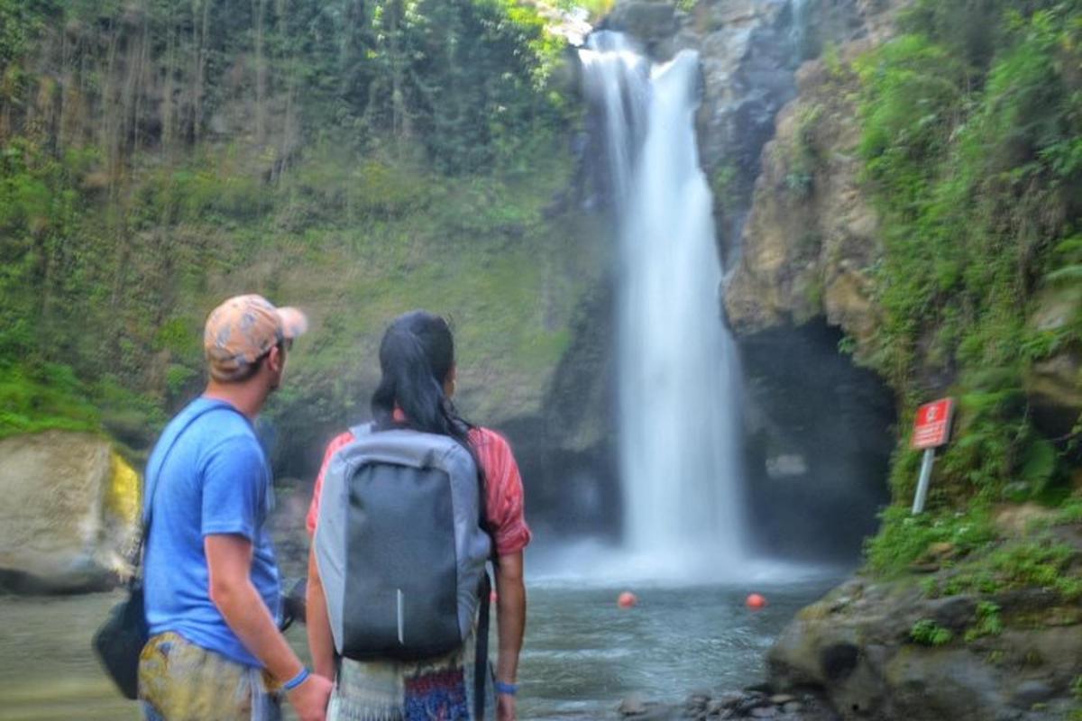 dua orang berdiri di depan air terjun