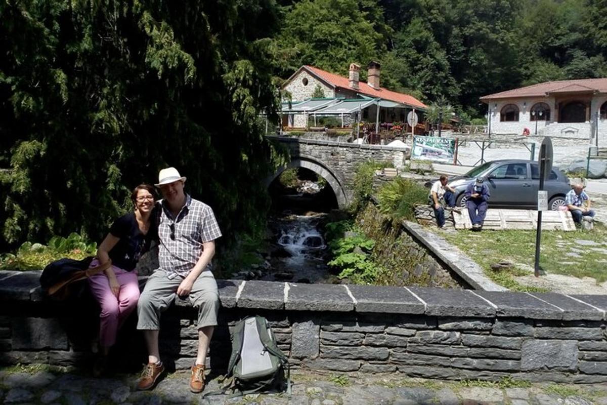 Ένας άντρας και μια γυναίκα κάθονται σε έναν πέτρινο τοίχο κοντά σε μια γέφυρα